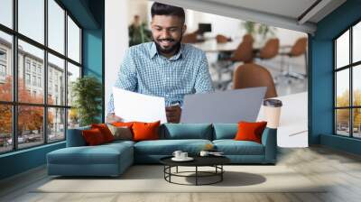 Business and people concept. Indian businessman with papers and laptop computer working at office Wall mural